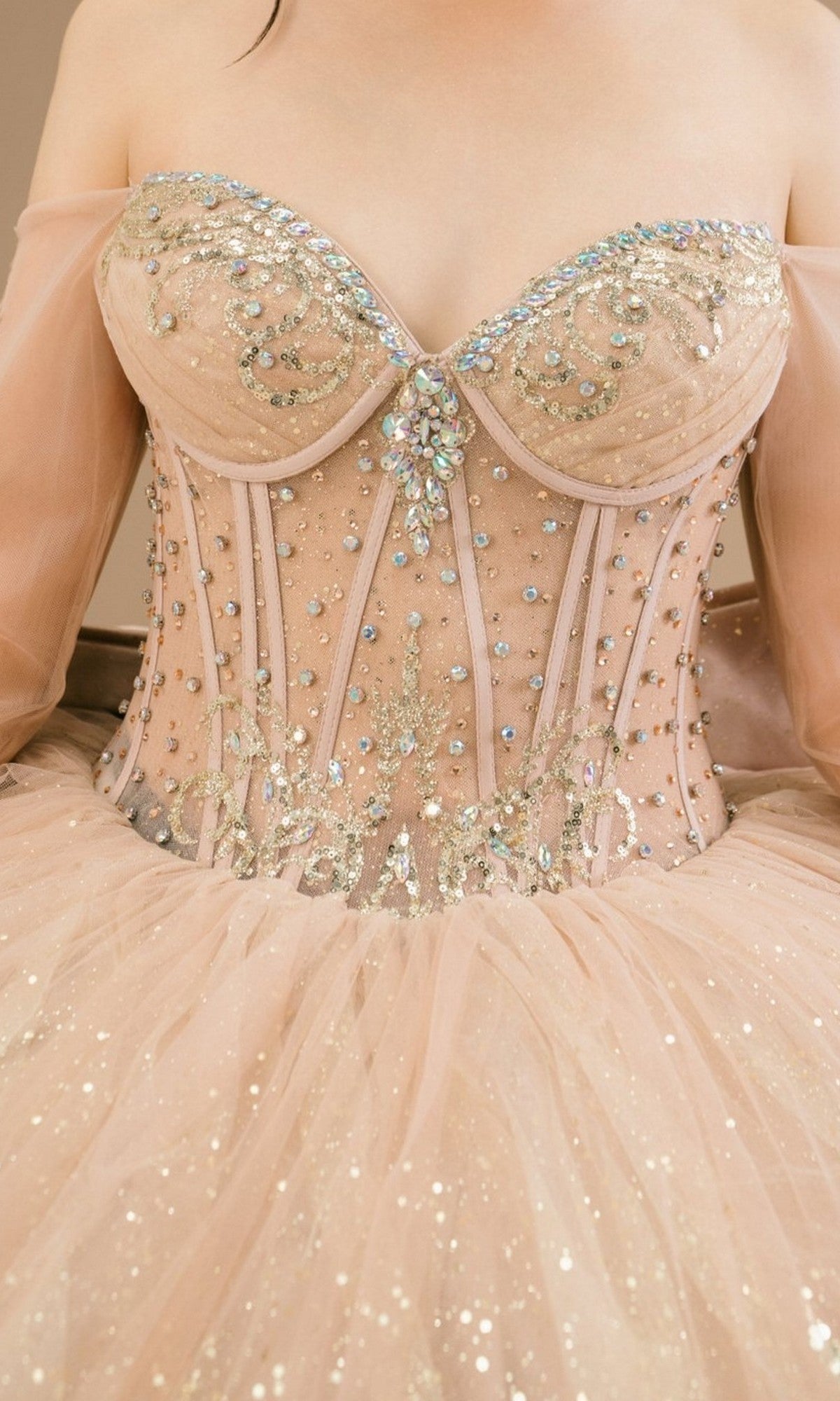 A close-up of a person wearing the Quinceanera Dress 8545JQ By Cinderella Couture, featuring a strapless ball gown design with sheer sleeves, an off-the-shoulder sweetheart neckline, and sparkling sequin embellishments.